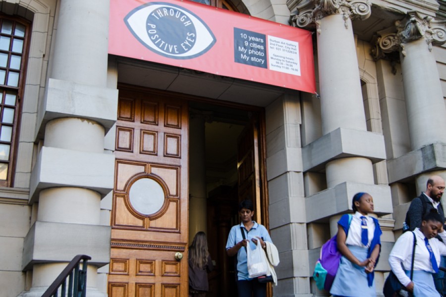 Schoolchildren exiting the Edwardian-inspired Durban City Hall beneath a Through Positive Eyes, Durban banner