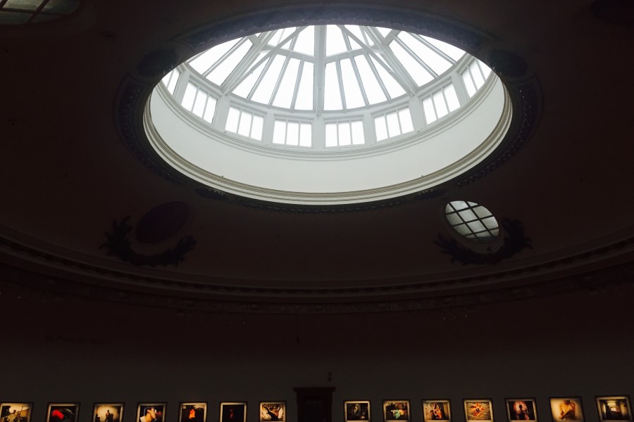 Individually illuminated prints in the dim central gallery beneath a large skylight