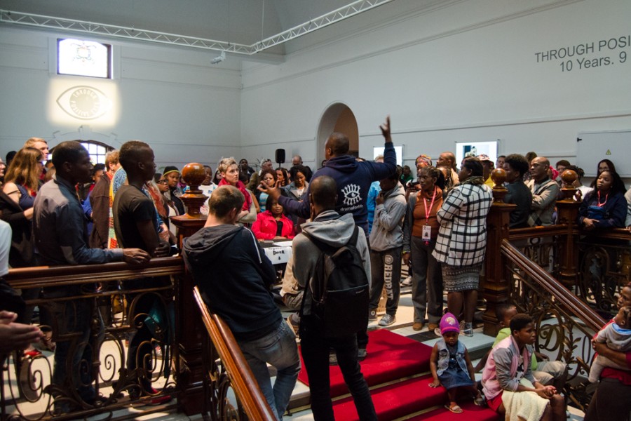 Person speaking before a large crowd at the exhibition opening
