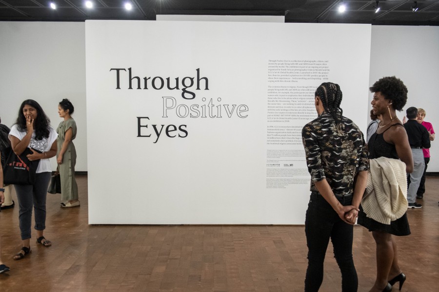 Visitors reading introductory text on the Through Positive Eyes title wall