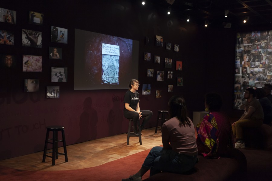 Kelly storytelling before a large audience in the Banishing Stigma Room