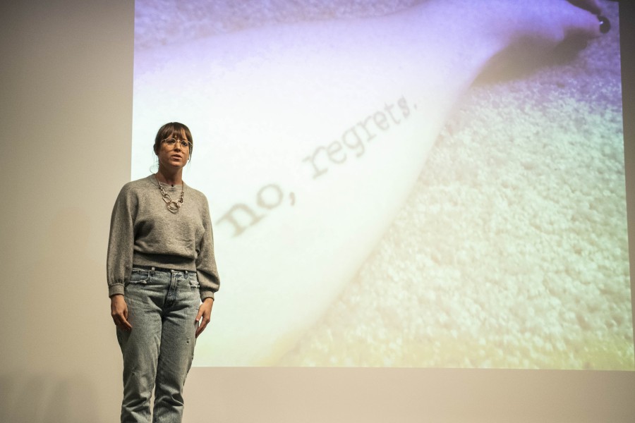 Kelly storytelling before an audience with one of her photographs projected behind her