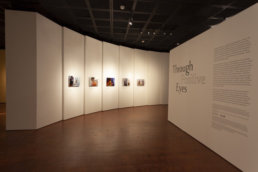 Gallery view with the Through Positive Eyes title wall, introductory text, and artivist photographs