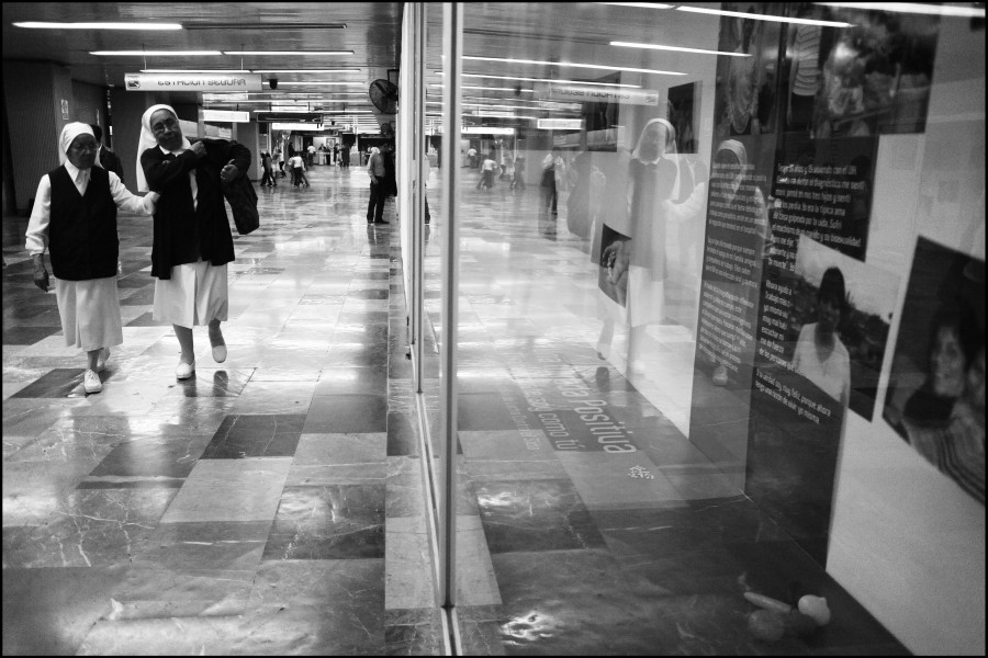 Two nuns walking past photographs and stories by Through Positive Eyes artivists