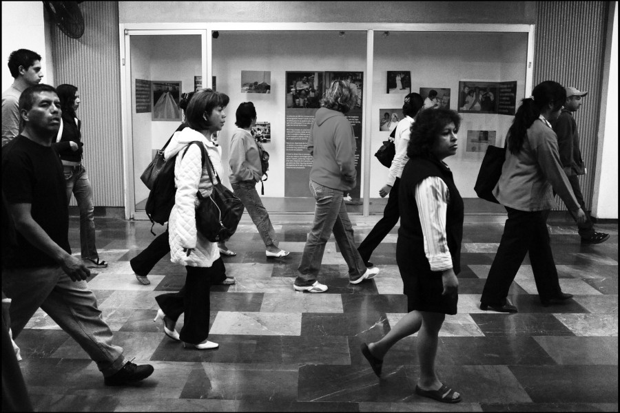People walking past the exhibition while some stop to view photographs and stories
